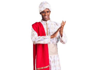 Afrikalı yakışıklı adam geleneksel Sherwani sari giysileri giyiyor ve alkışlıyor mutlu ve neşeli, gururlu elleri bir arada alkışlıyor. 