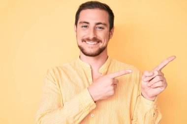 Gündelik kıyafetler giyen, gülümseyen ve kameraya bakan genç, yakışıklı bir adam.. 