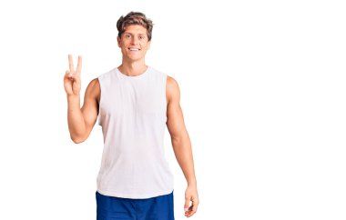 Kolsuz tişört giyen, kameraya gülümseyen ve zafer işareti yapan genç yakışıklı bir adam. İki numara.. 