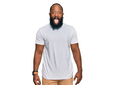 Genç, Afro-Amerikan bir adam, günlük beyaz tişört giyiyor. Dilini komik bir ifadeyle dışarı çıkarıyor. duygu kavramı. 
