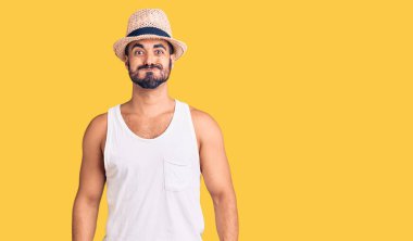 Yaz şapkası takan İspanyol genç adam komik yüzlü yanakları şişiriyor. Havayla şişmiş ağız, çılgın bir ifade.. 