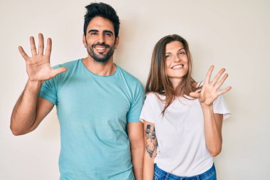 Güzel, genç bir çift sevgili 10 numarayı gösterip işaret ederken kendinden emin ve mutlu gülümsüyor.. 