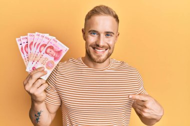 Elinde 100 Yuan 'lık Çin banknotları tutan beyaz bir adam mutlu bir şekilde el ve parmak işareti yapıyor. 