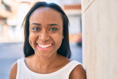 Genç Afrikalı Amerikalı kadın gülümseyerek şehirde mutlu mesut yürüyor..