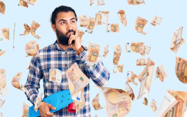 Yüzü ciddi bir şekilde kayan genç bir Arap, eli çenesinde soru sormayı düşünüyor. Kafa karıştırıcı bir fikir.