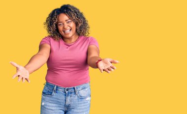 Genç Afro-Amerikan artı cüsseli kadın. Günlük kıyafetler giyiyor. Gülümsüyor, yardım eli uzatıyor ve kabul ediyor.. 