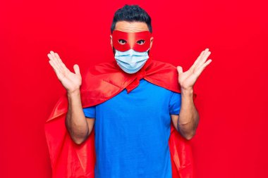 Süper kahraman kostümü ve tıbbi maske giyen İspanyol genç adam ağzı açık kalmış, korkmuş ve hayrete düşmüştü. 