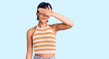 Kısa saçlı, esmer, sıradan kıyafetler giyen, gözleri elle kaplayan, ciddi ve üzgün görünen genç bir kadın. Görme, saklama ve reddetme konsepti 