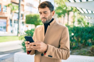 Zarif ceketli yakışıklı bir iş adamı. Açık havada akıllı telefon kullanıyor.