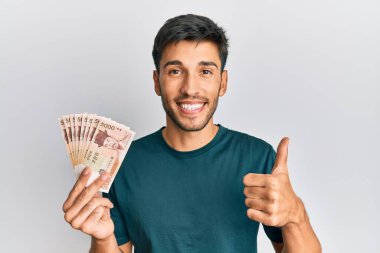 Güney Kore 'yi elinde tutan yakışıklı genç adam mutlu ve olumlu gülümseyen banknotlar kazandı. 