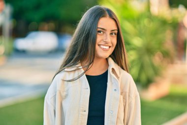 Genç İspanyol kız gülümseyerek şehirde mutlu mesut dikiliyor..