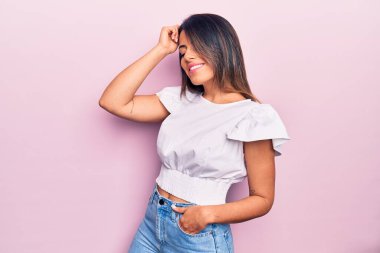 Genç, güzel, esmer, sıradan kıyafetler giyen mutlu ve kendinden emin bir kadın. İzole edilmiş pembe arka planda yüzünde bir gülümsemeyle duruyorum.