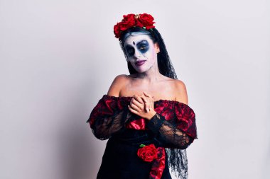 Meksika makyajlı genç bir kadın ellerini birleştirip gülümsüyor ve gevşemiş ve neşeli gülümsüyor. Başarı ve iyimserlik 