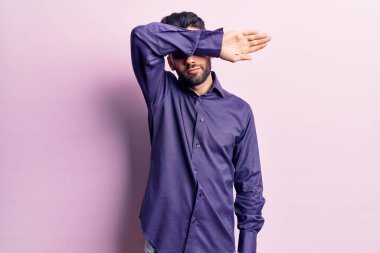 Sakallı, sıradan gömlek giyen, kollarıyla gözlerini kapatan, ciddi ve üzgün görünen genç yakışıklı bir adam. Görme, saklama ve reddetme konsepti 