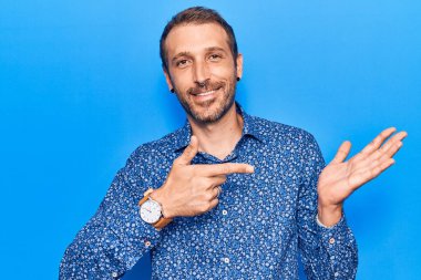 Gündelik kıyafetler giyen genç yakışıklı adam kameraya hayret ediyor ve gülümsüyor.. 