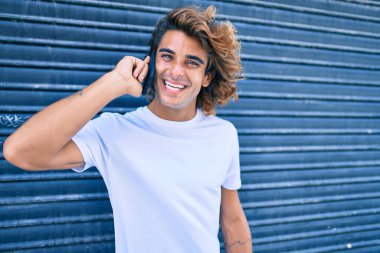 Genç İspanyol adam şehrin caddesinde akıllı telefondan konuşuyor.