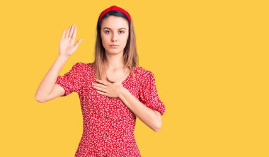 Elbise giyen ve el pençe divan duran genç ve güzel bir kız sadakat yemini ediyor. 