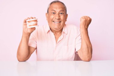 Takma dişleri olan yaşlı yakışıklı adam Talbe 'da oturmuş gururla haykırıyor, zaferi kutluyor ve kollarını kaldırarak başarıyı kutluyor. 