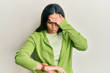 Genç esmer kadın gündelik kıyafetler giyip saatine bakıyor. Endişeli, geç kalmaktan korkuyor. 