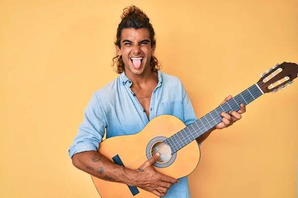 年轻人弹奏古典吉他手伸出舌头 带着滑稽的表情高兴极了 — 图库照片