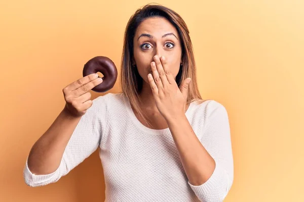 Jovem Bela Mulher Segurando Donut Cobrindo Boca Com Mão Chocado — Fotografia de Stock