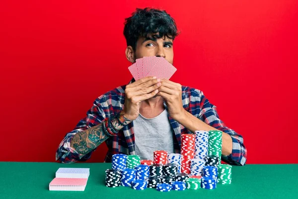 Young Hispanic Man Playing Gambling Poker Covering Face Cards Smiling — Stock Photo, Image