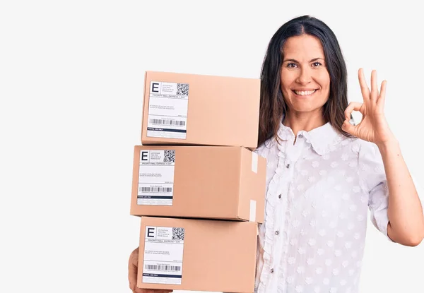 Young Beautiful Brunette Woman Holding Delivery Cardboard Package Doing Sign — Stock Photo, Image
