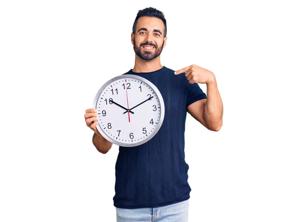 Jeune Homme Hispanique Tenant Une Grande Horloge Pointant Doigt Sourire — Photo