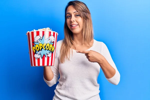 Joven Hermosa Mujer Sosteniendo Palomitas Sonriendo Feliz Señalando Con Mano —  Fotos de Stock