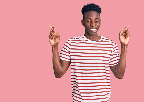 若いアフリカ系アメリカ人の男性がカジュアルな服を着て 指をジェスチャー希望と目を閉じて笑顔を渡った 幸運と迷信の概念は — ストック写真
