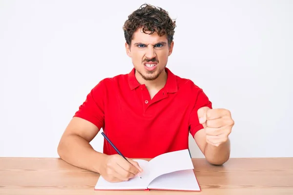 Joven Hombre Caucásico Con Pelo Rizado Escribiendo Cuaderno Sentado Mesa —  Fotos de Stock