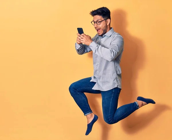 Mladý Pohledný Latinskoamerický Muž Brýlemi Poskakujícími Úsměvem Tváři Použití Smartphone — Stock fotografie