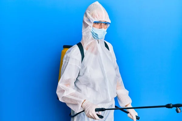 科维德专业人员 身穿防污防护服和消毒剂喷雾 在蓝色背景上对表面进行除污和消毒 — 图库照片