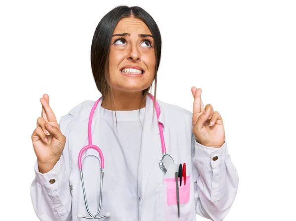 Mulher Hispânica Bonita Vestindo Uniforme Médico Estetoscópio Gesto Dedo Cruzado — Fotografia de Stock