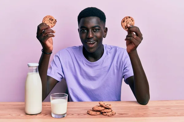 年轻的非洲裔美国人喝着一杯新鲜的牛奶 饼干笑着 笑得很大声 因为这是个可笑的疯狂笑话 — 图库照片