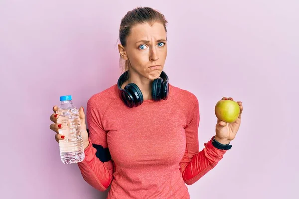 Schöne Kaukasische Sportlerin Mit Wasserflasche Und Grünem Apfel Skeptisch Und — Stockfoto