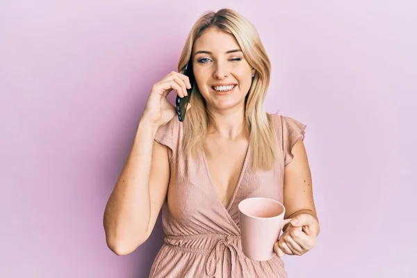 Jovem Caucasiana Falando Smartphone Bebendo Uma Xícara Café Piscando Olhando — Fotografia de Stock