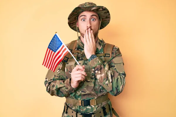 カモフラージュ軍の制服を着た若い白人男性は 手で口を覆い ショックを受け 間違いを恐れてウサの旗を持っていた 驚きの表情 — ストック写真
