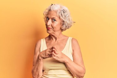 Kıdemli, gri saçlı, sıradan kıyafetler giyen, el ele tutuşan, gülümseyen, rahat ve neşeli bir kadın. Başarı ve iyimserlik 