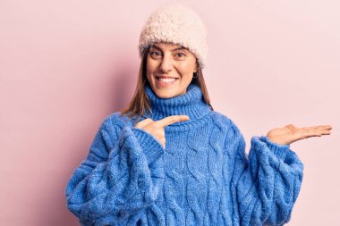 Kışlık giysiler giyen genç ve güzel bir kadın kameraya hayret ediyor ve gülümsüyor.. 