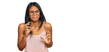 Genç Afro-Amerikalı kadın günlük kıyafetler ve gözlük takıyor. İfadelerinden iğreniyor ve tiksiniyor. Tiksinti ifadesi takınıyor.. 