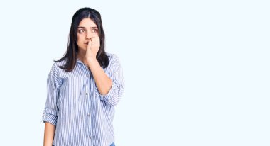 Çizgili gömlek giyen genç ve güzel bir kız stresli ve gergin görünüyor. Elleri ağızdan tırnak yiyor. anksiyete. 