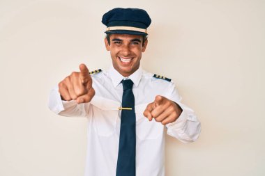 İspanyol üniformalı genç adam seni ve kamerayı işaret ediyor, pozitif ve neşeli gülümsüyor. 