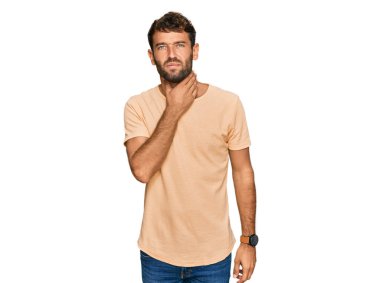 Sakallı, sıradan tişörtlü, boynu ağrıyan, boğazı ağrıyan, grip, mantar ve enfeksiyon kapmış yakışıklı bir genç. 