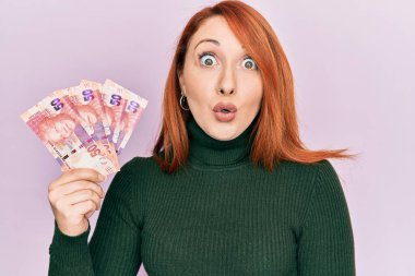 Güney Afrika 'nın 50 rand' ini elinde tutan güzel kızıl saçlı kadın. Korkmuş ve hayrete düşmüştü. 