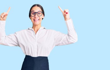 Güzel, esmer, profesyonel garson önlüğü giyen genç bir kadın. Şaşırmış, şaşırmış, parmaklarıyla işaret ediyor ve kollarını kaldırıyordu.. 