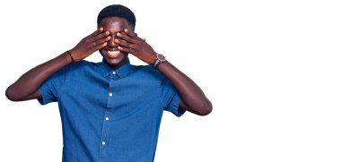 Genç Afro-Amerikan adam günlük kıyafetler giyiyor. Gözleri kapatıyordu. Neşeli ve komik gülümsüyordu. kör kavram. 