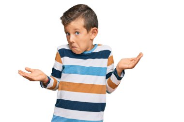 Gündelik kıyafetler giyen, kafası karışmış, kolları ve elleri havada, sevimli beyaz bir çocuk. şüphe kavramı. 