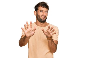 Sakallı, sıradan tişörtler giyen yakışıklı bir genç. Avuçlarını hareket ettiriyor. Korkmuş ve iğrenç bir ifadeyle reddediyor. Dur ve yasakla. 