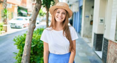 Genç sarışın kadın tatilde gülümsüyor. Mutlu bir şekilde caddede yürüyor.